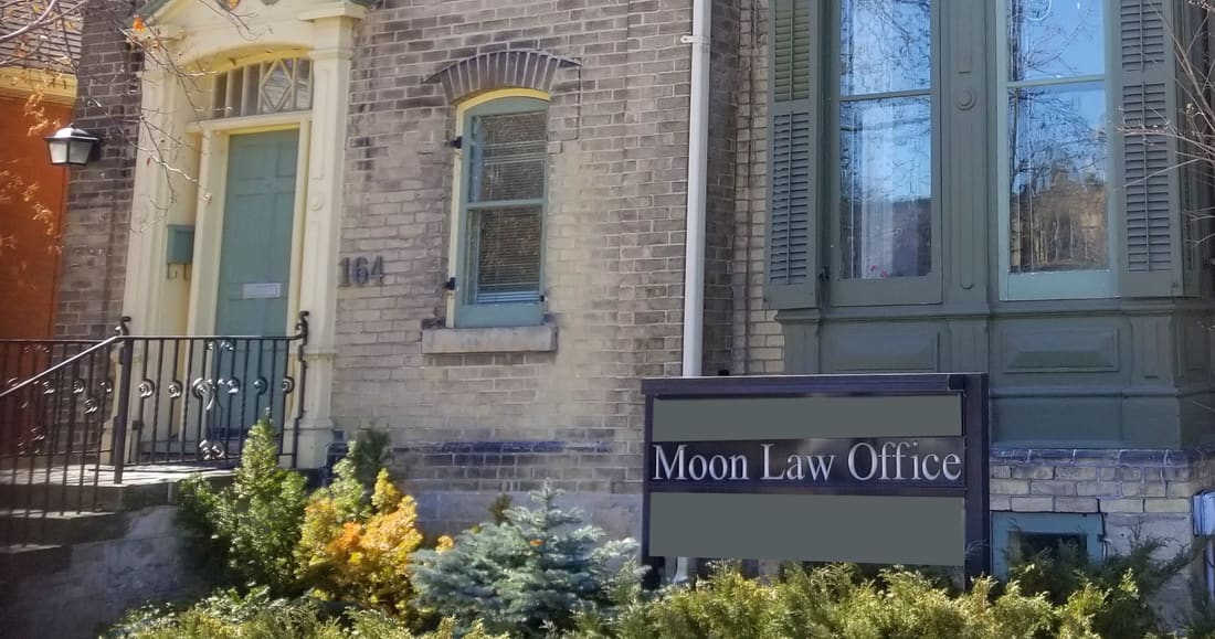 The front steps and green door of 164 Norfolk St, with the number beside the door and the Moon Law Office sign in the garden.